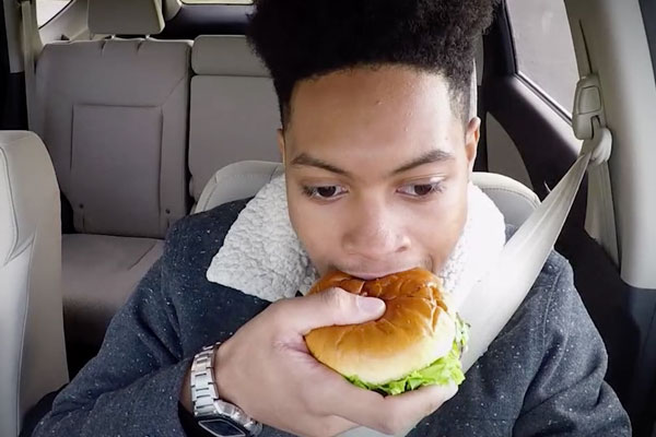 a teen eating a sandwich while driving