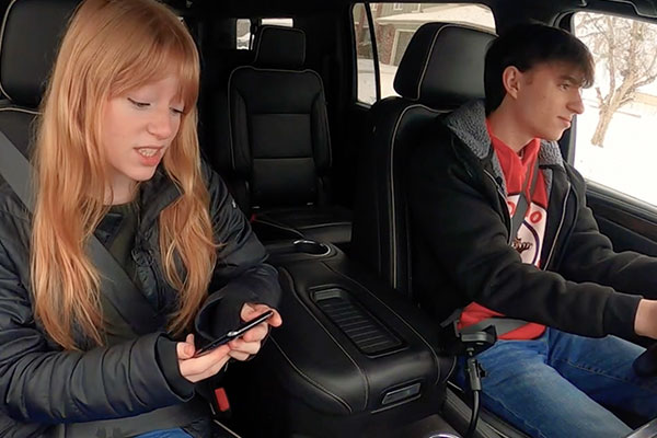 two teens in a car one looking at a cellphone