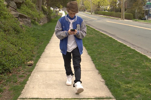 Boy walking down the street on his cellphone