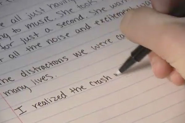 close up of a hand writing a letter on lined paper