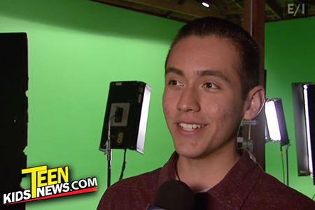 a boy being interviewed with a green screen behind him