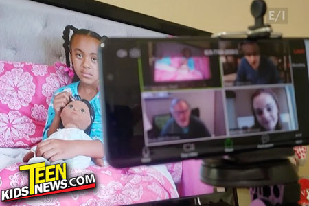 a screen with a young girl behind a phone with a zoom meeting