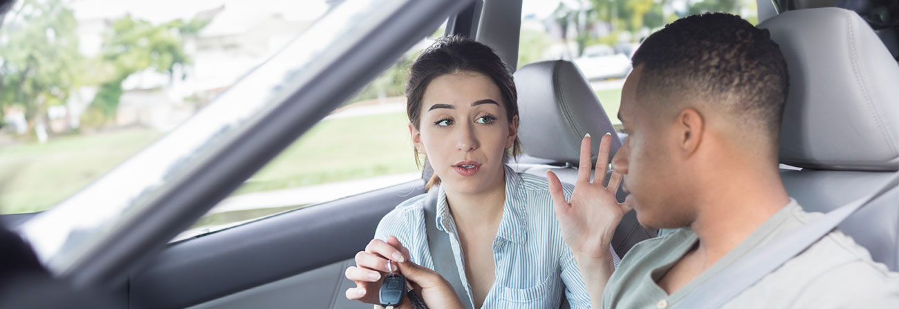 teen girl taking car keys from a teen boy driver