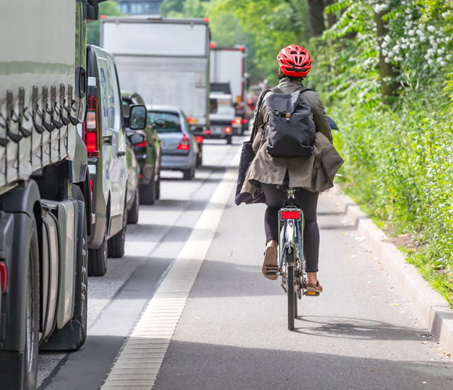student on a bike next to cars back view